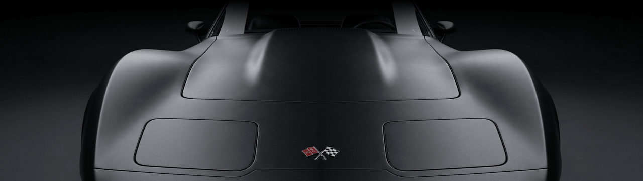 A matte black classic sports car viewed from above, featuring pop-up headlights and crossed flag emblems on the hood, set against a dark background.