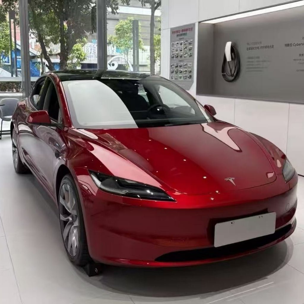 A shiny red Tesla with Deep Red Glossy SelfRepair Nano-Coated PPF is showcased in a modern showroom with large windows and white walls, reflecting natural light.