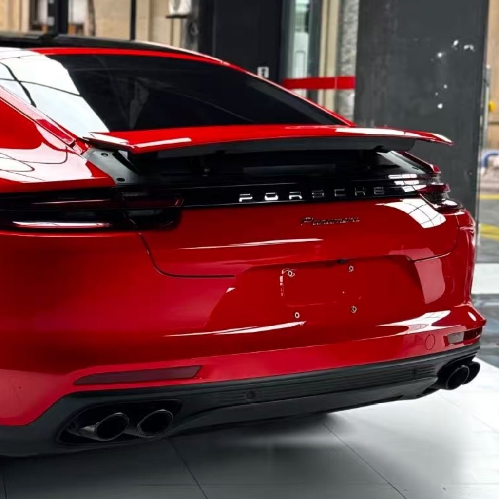 Rear view of a red Porsche Panamera indoors, showcasing its spoiler, dual exhausts, dark-tinted windows, and glossy finish protected by Nexthor™ Ferrari Red SelfRepair Nano PPF Glossy. No visible license plate.
