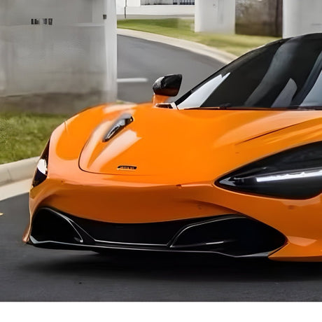 A McLaren, finished in McLaren Orange Glossy SelfRepair Nano-Coated PPF, is parked beside a curb with grass and white pillars. Only the front and side protected by the nano-coated PPF are visible.