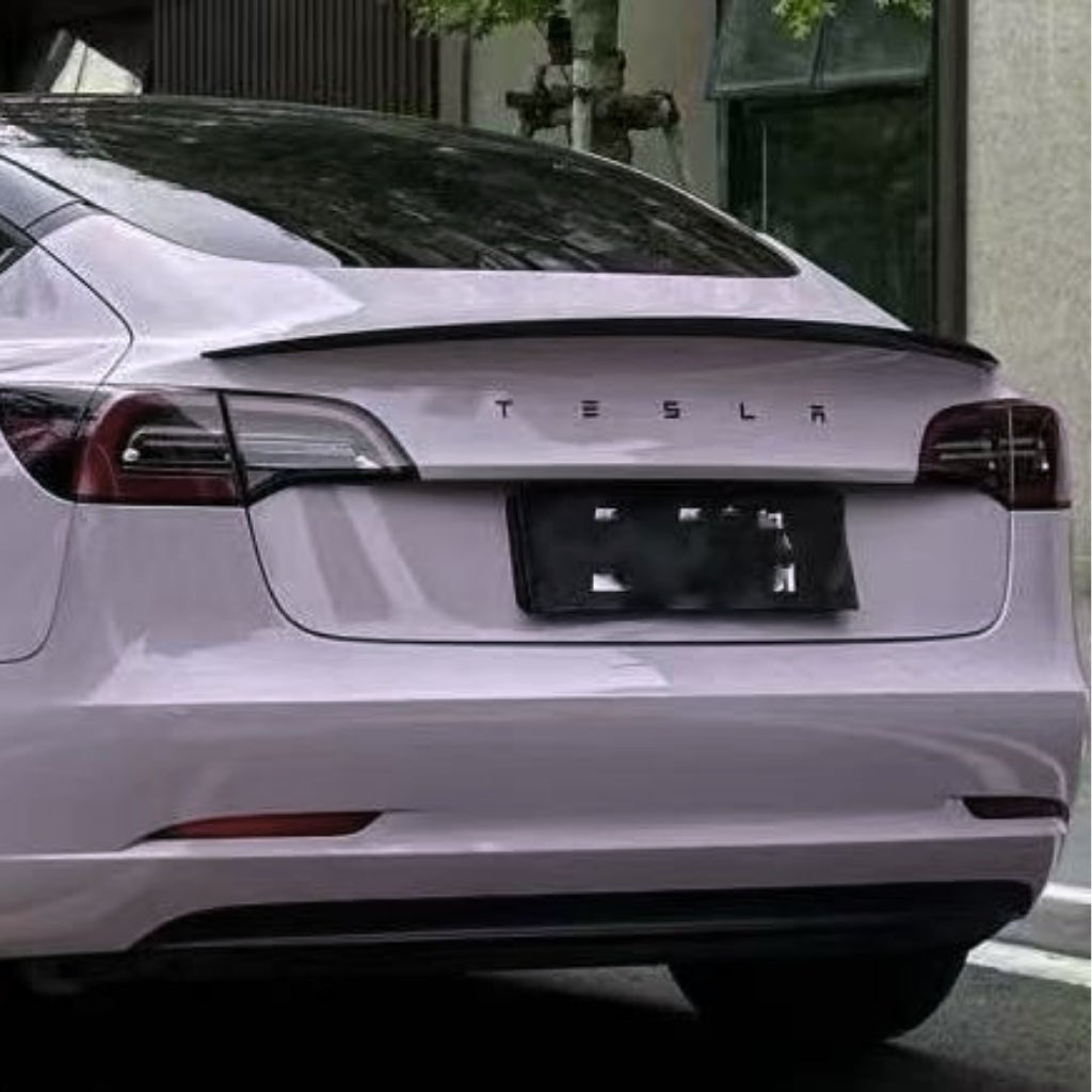 Rear view of a white Tesla parked on the street, with the Tesla logo above the license plate. Tail lights and rear window are visible, while Misty Gray Purple Glossy SelfRepair Nano-Coated PPF adds subtle color protection to the paint.