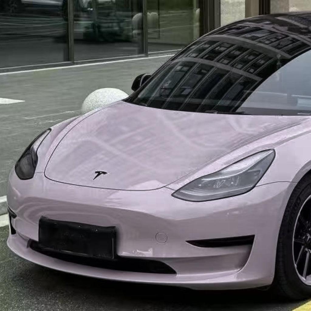 A light purple Tesla with Misty Gray Purple Glossy SelfRepair Nano-Coated PPF is parked by a glass building, its hood and windshield reflecting windows. The farebná PPF fólia adds vibrant color while protecting the paint.
