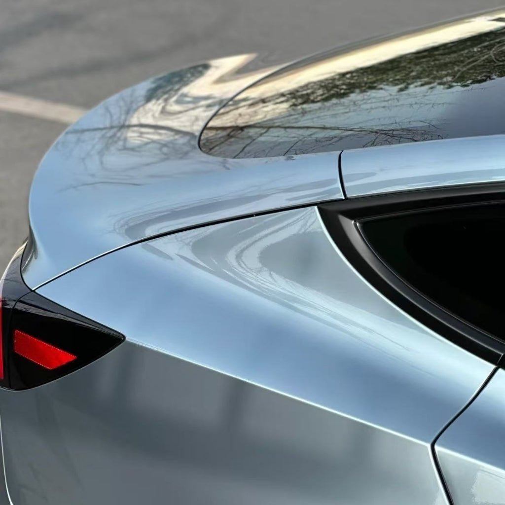 Close-up of a modern silver car's rear with sleek curves, taillight, and rear window protected by Gray Sparkle Pearl SelfRepair Nano-Coated PPF—an advanced ochranná fólia na auto with samoliečivá nano technológia reflecting trees and sky.
