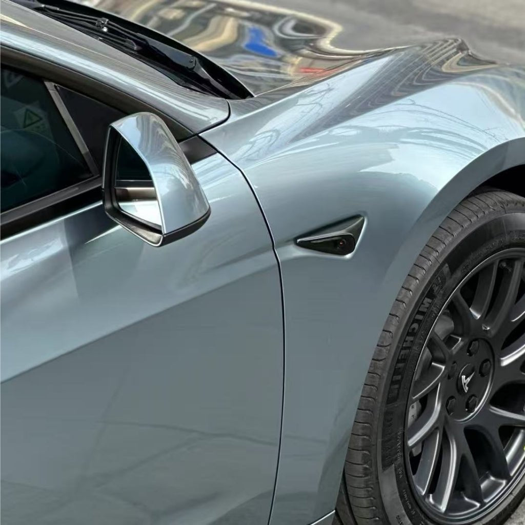 Close-up of the front left side of a metallic gray car with Gray Sparkle Pearl SelfRepair Nano-Coated PPF, highlighting the side mirror, door, black alloy wheel, and fender with building reflections on its glossy surface.