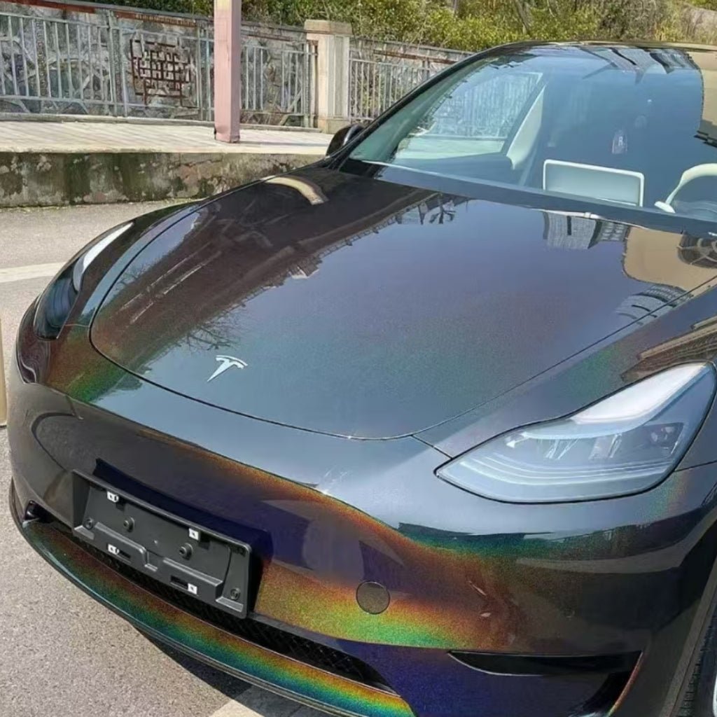 A Tesla with a striking Black Galaxy Glossy SelfRepair Nano-Coated PPF paint job is parked on a street near a metal fence and stone sidewalk.