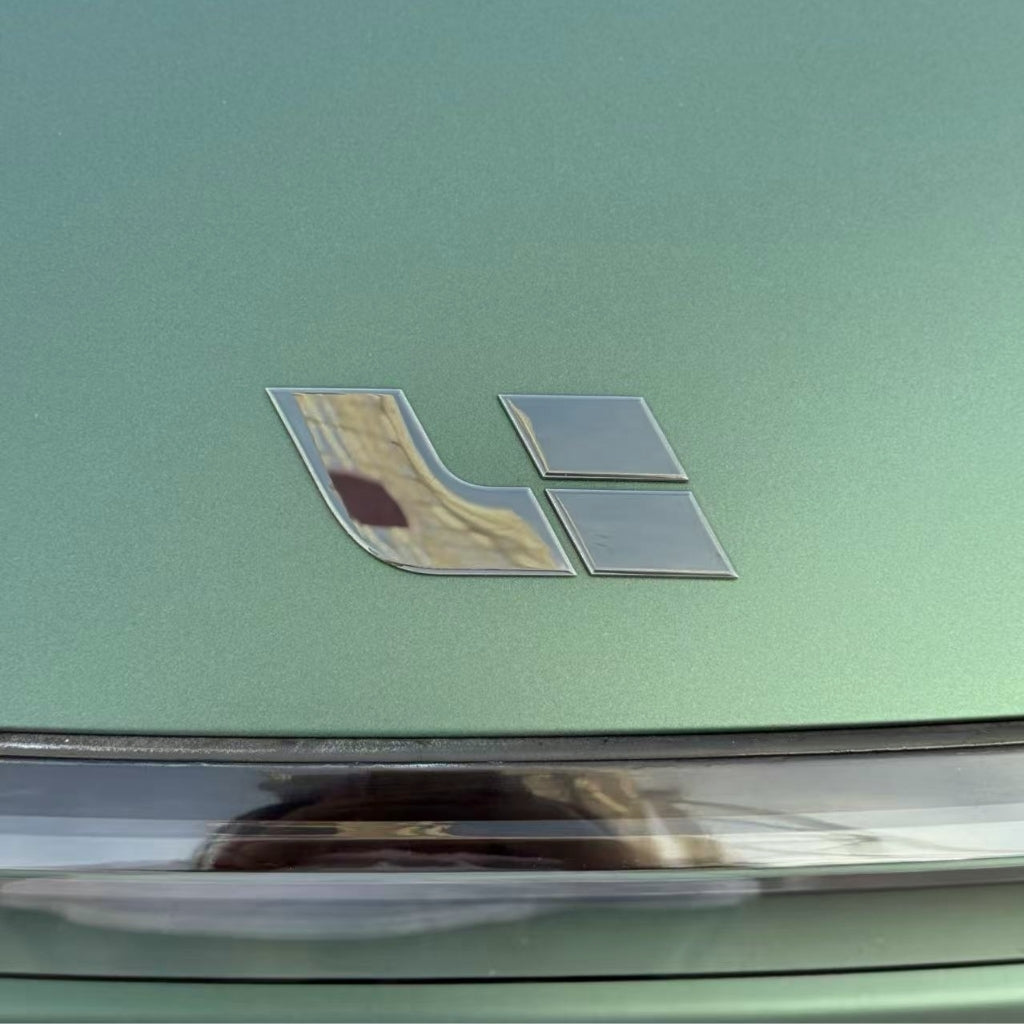 A close-up of a metallic green car hood with the Li Auto logo highlights the protection and stylish finish provided by Dark Green Matte SelfRepair Nano-Coated PPF, featuring two silver geometric shapes and a glimpse of the windshield below.
