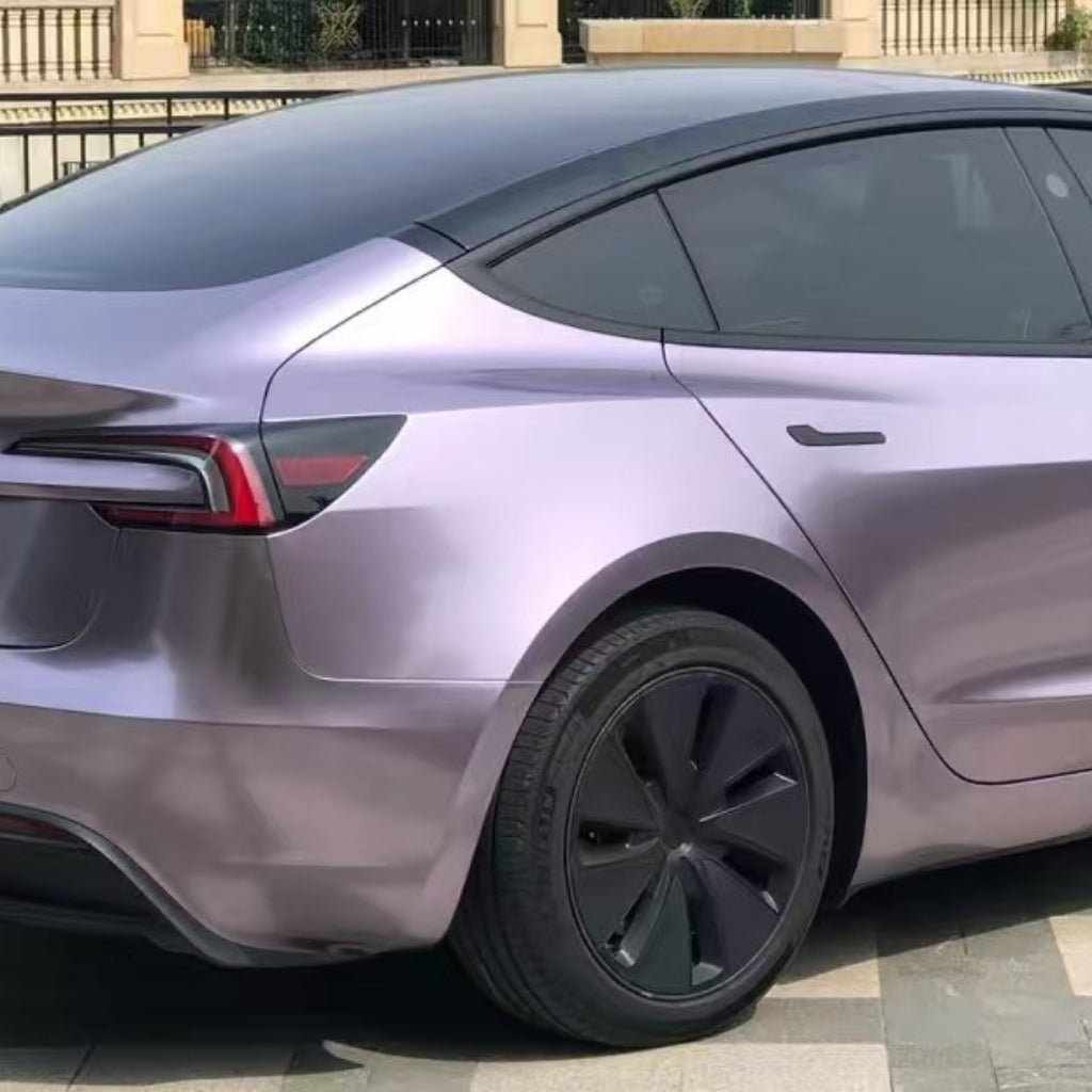 A metallic light purple Tesla Model 3 in Sunshine Purple Liquid Metallic Matte SelfRepair Nano-Coated PPF is parked on a tiled surface, viewed from the rear side. It features tinted windows, black aerodynamic wheels, and a sleek PPF film finish.
