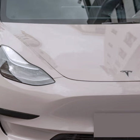 Close-up of a light-colored Tesla’s front with headlight, hood logo, and windshield—upgraded by Sky Mirror Pink Glossy SelfRepair Nano-Coated PPF for standout looks and extra ochranná fólia na auto protection.