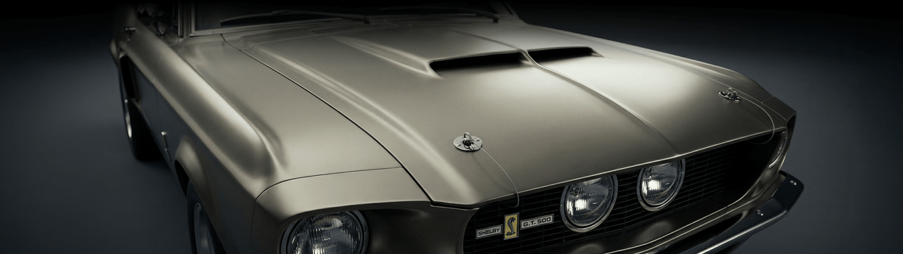 Close-up of the front hood and grille of a vintage muscle car, featuring a metallic finish, prominent hood scoop, dual headlights, and Shelby GT 500 badging.