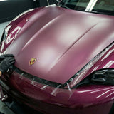 A person in black gloves applies Transparent Matte SelfRepair Nano-Coated PPF to the hood of a maroon Porsche, with the emblem visible and headlights partially covered.