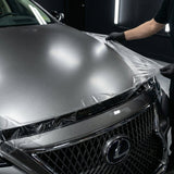 A person in black gloves applies Transparent Matte Sparkle SelfRepair Nano-Coated PPF to the hood of a silver Lexus in a well-lit garage, using self-healing nano technology for advanced paint protection.