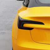 Close-up of the rear left side of a bright yellow car wrapped in Amber Yellow Glossy SelfRepair Nano-Coated PPF, highlighting the taillight and trunk against a smooth gray background—a perfect showcase for its self-repair nano layer.