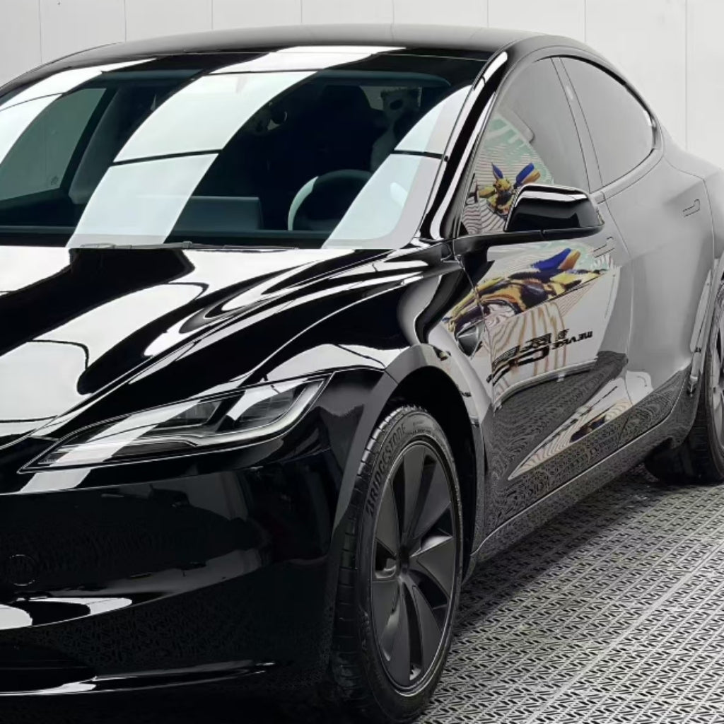 A black Tesla Model S with Black Glossy SelfRepair Nano-Coated PPF is parked indoors on a patterned floor, its paint reflecting the lights and surroundings while the PPF provides extra protection.