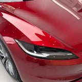 Close-up of the front left headlight and fender of a shiny red car protected by Deep Red Glossy SelfRepair Nano-Coated PPF, reflecting bright indoor lights and its surroundings.
