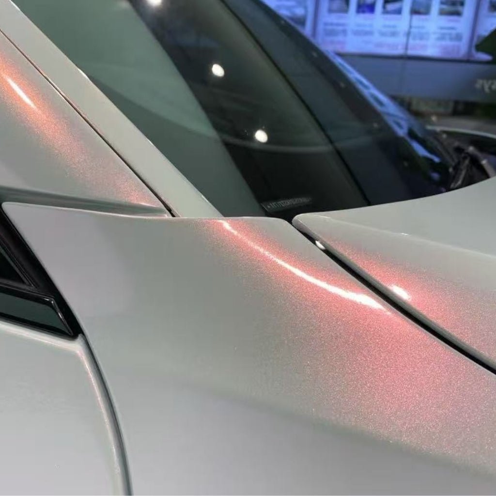 Close-up of a car's hood and windshield featuring a smooth, pearlescent finish with White Diamond Pink Glossy SelfRepair Nano-Coated PPF, shimmering with pink highlights under the light.