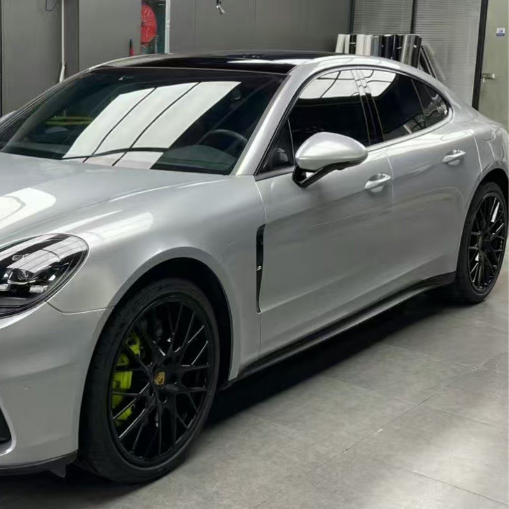 A luxury silver sports sedan with black rims and green calipers is parked indoors under bright lights, its shine and protection boosted by GT Silver Liquid Metallic Glossy SelfRepair Nano-Coated PPF.