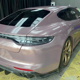 A Porsche sports car in metallic mauve, wrapped in Ice Berry Pink Liquid Metallic Glossy SelfRepair Nano-Coated PPF, sits indoors on a yellow-patterned floor. Gold wheels and dark-tinted windows complete the striking appearance.