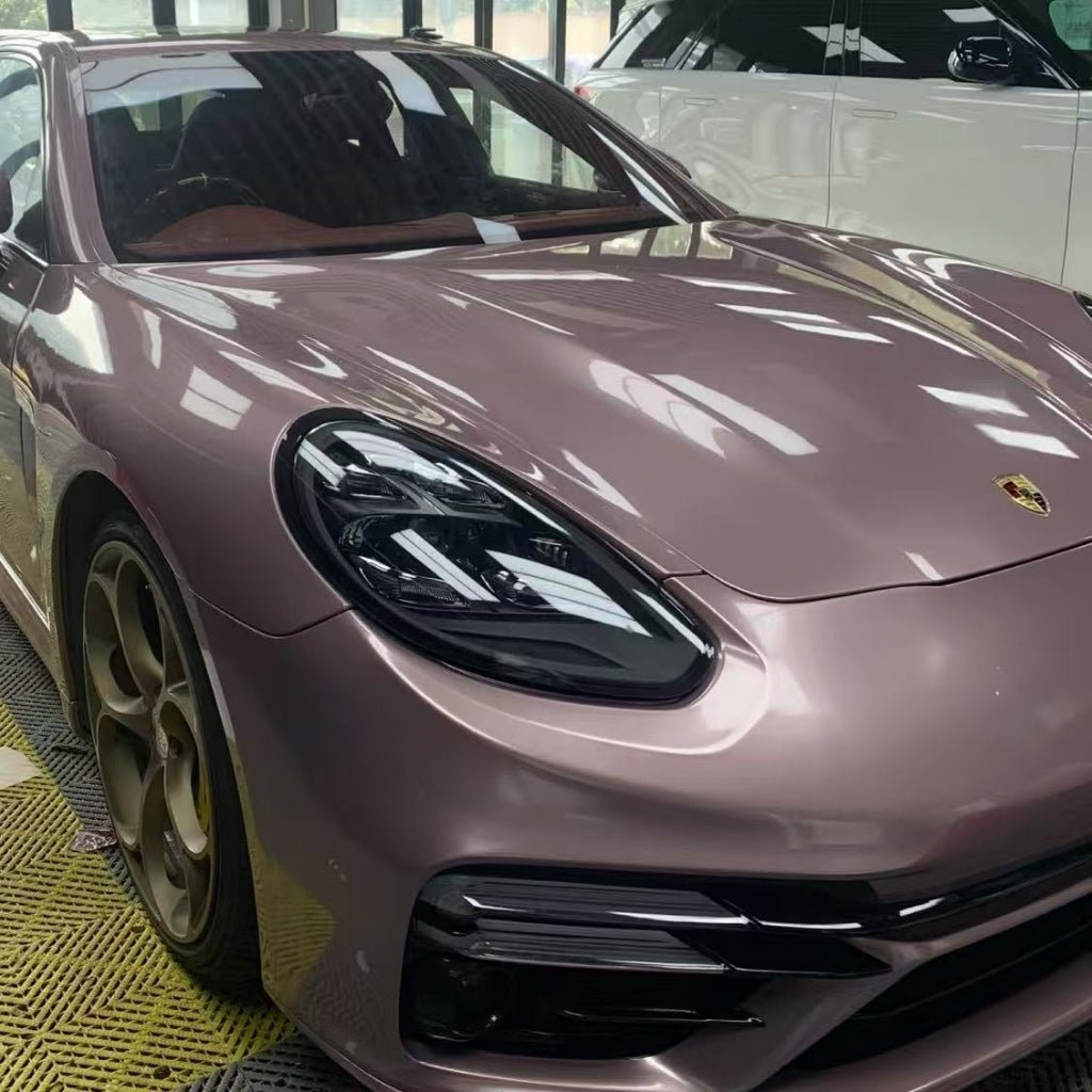 A rose gold Porsche sports car, protected by Ice Berry Pink Liquid Metallic Glossy SelfRepair Nano-Coated PPF, is parked indoors beside a white SUV. Window reflections highlight the car's glossy nano-coated PPF film finish.