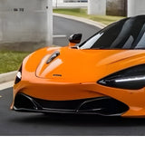 A McLaren, finished in McLaren Orange Glossy SelfRepair Nano-Coated PPF, is parked beside a curb with grass and white pillars. Only the front and side protected by the nano-coated PPF are visible.