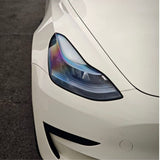 Close-up of the front left headlight on a sleek, white car with blue-purple reflections, protected by Pepper White Glossy SelfRepair Nano-Coated PPF and parked on dark asphalt.
