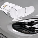 Close-up of the front left headlight and hood of a white Porsche with Porsche Gray Glossy SelfRepair Nano-Coated PPF, featuring a shiny surface and window grid reflections for superior paint protection.