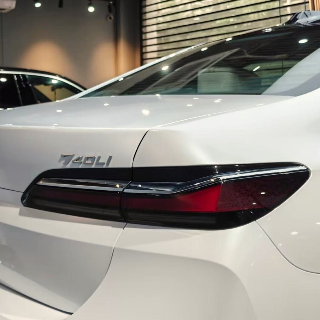 Close-up of a white BMW 740Li with Arctic White Sparkle Glossy SelfRepair Nano-Coated PPF, highlighting the model badge and modern taillights in a bright showroom.