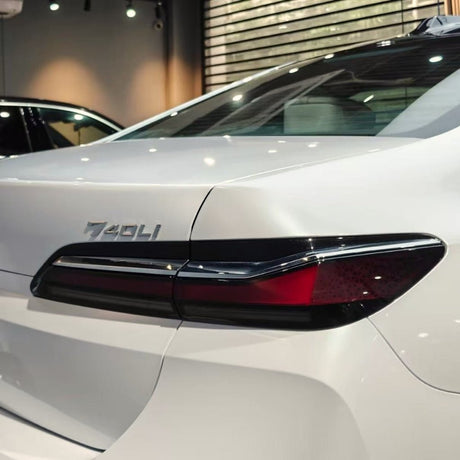 Close-up of a white BMW 740Li with Arctic White Sparkle Glossy SelfRepair Nano-Coated PPF, highlighting the model badge and modern taillights in a bright showroom.