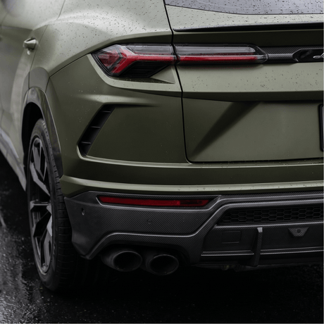 Close-up of a matte green luxury SUV with Matte Carbon Fiber SelfRepair Nano-Coated PPF, showing raindrops on the surface, modern tail lights, dual exhausts, and black trim glistening on wet pavement.