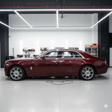 A maroon luxury sedan, safeguarded by Diamond Black Rose Glossy SelfRepair Nano-Coated PPF, sits in a modern garage with white walls, LED ceiling lights, and shelves filled with tools and supplies.