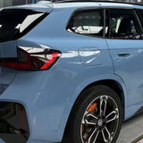 A close-up of the rear side of a blue SUV with Blue Lagoon Glossy SelfRepair Nano-Coated PPF highlights the taillight, rear window, fuel cap, and a black and silver rim with orange brake caliper. The car is parked indoors for ochrana laku vozidla.