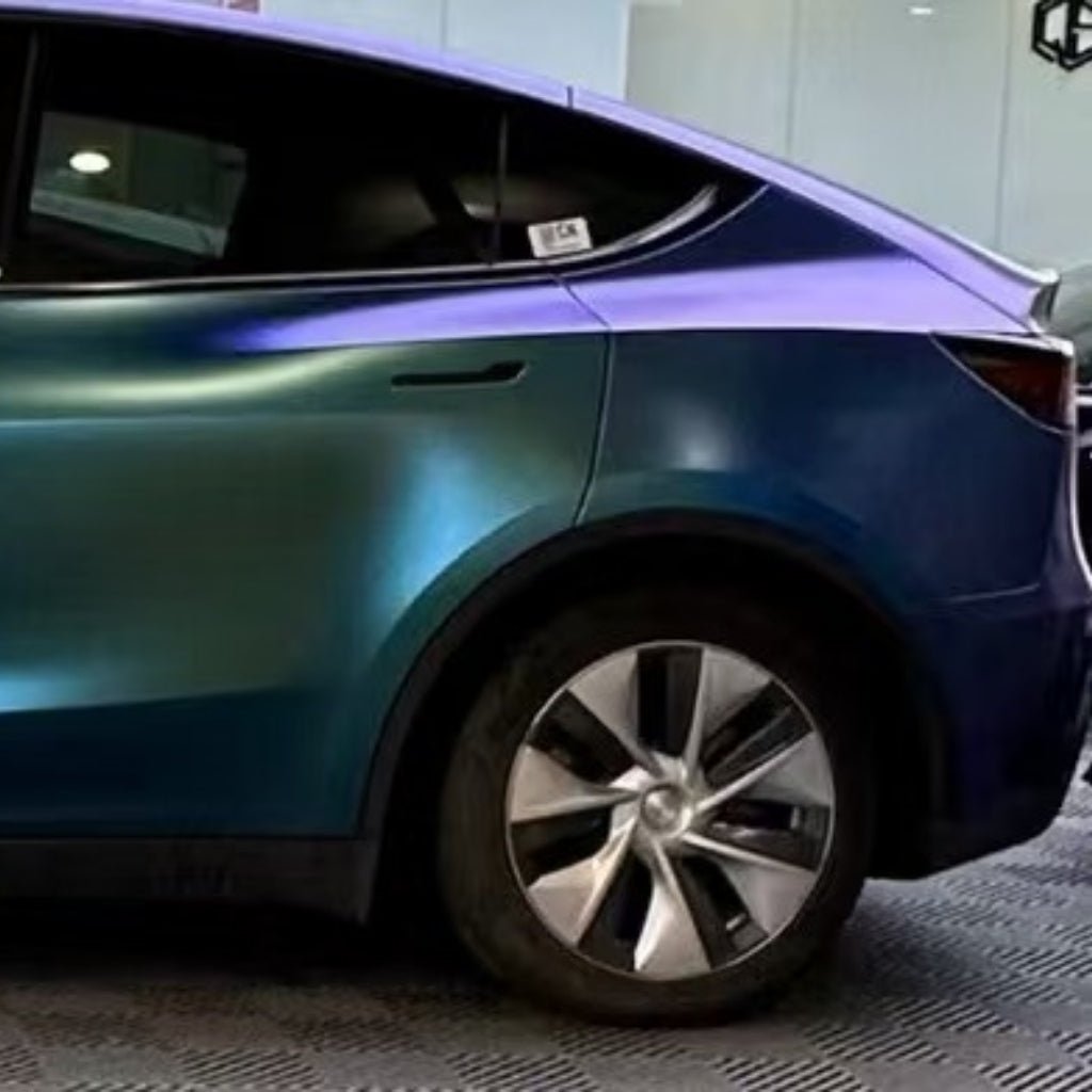 A partial side view of a modern car features a Chameleon Purple Blue Green Matte SelfRepair Nano-Coated PPF, highlighting the rear wheel, door, and window in a well-lit indoor showroom.