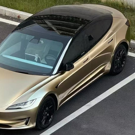 A Tesla Model S wrapped in Champagne Gold Liquid Matte Metallic SelfRepair Nano-Coated PPF, featuring black wheels and a black roof, is parked by the curb next to green grass.