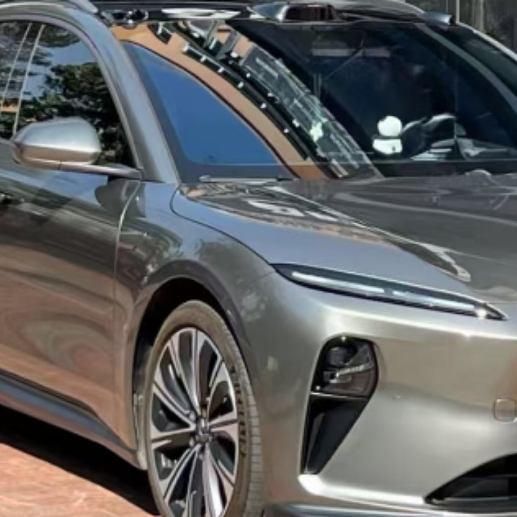 A close-up of a modern silver electric car parked outdoors, highlighting sleek front and side design, large alloy wheels, and chrome reflections protected by Chrome Black Liquid Metallic Glossy SelfRepair Nano-Coated PPF.