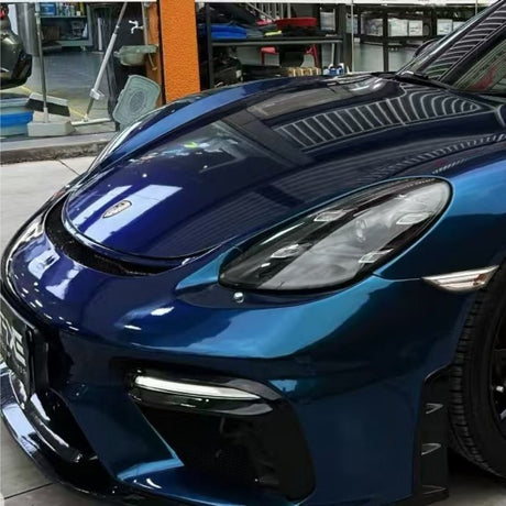 Close-up of a shiny dark blue sports car front, protected by Diamond Dark Shadow Blue Glossy SelfRepair Nano-Coated PPF, parked indoors with reflections on the hood and windshield highlighting the premium film.