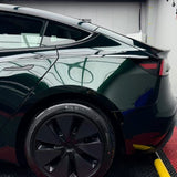 A close-up of the rear side of a shiny black car showcases the Diamond Emerald Glossy SelfRepair Nano-Coated PPF, highlighting its self-repair finish on the back wheel, tinted windows, and sleek curves reflecting lights in an indoor garage.