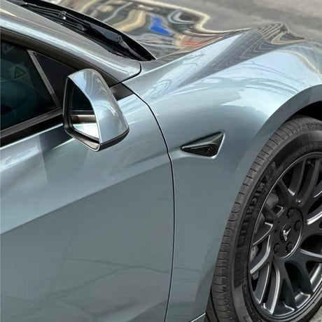Close-up of the front left side of a metallic gray car with Gray Sparkle Pearl SelfRepair Nano-Coated PPF, highlighting the side mirror, door, black alloy wheel, and fender with building reflections on its glossy surface.
