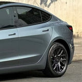 A close-up of a sleek silver car with Gray Sparkle Pearl SelfRepair Nano-Coated PPF on the rear door and wheel, featuring tinted windows, parked by a beige wall.