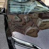 A black car’s hood and windshield, wrapped in Black Galaxy Glossy SelfRepair Nano-Coated PPF, reflect nearby buildings for a mirror-like effect while providing špičková ochrana karosérie.