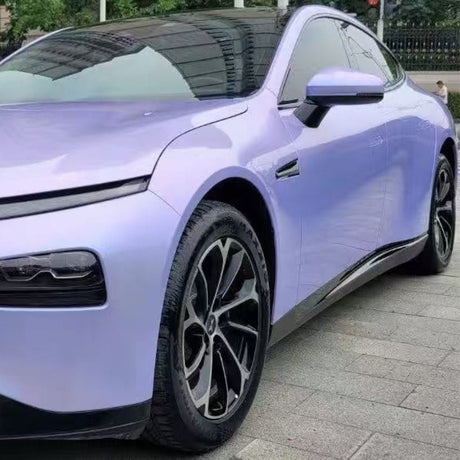 A sleek electric car with a Charm Silver to Purple Matte SelfRepair Nano-Coated PPF is parked on the street. Its black multi-spoke rims and tinted windows complete the look while the nano-coating keeps its finish flawless.