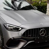 A close-up of a Mercedes-Benz front in AMG Mountain Gray Matte SelfRepair Nano-Coated PPF, showcasing the grille, emblem, sleek headlights, and palm tree reflections—all safeguarded by advanced self-healing nano technology.