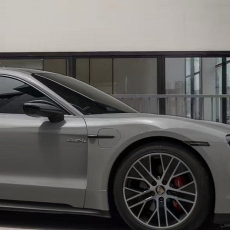A sleek silver sports car, viewed indoors by large glass windows, showcases its front wheel and door enhanced with Porsche Gray Matte SelfRepair Nano-Coated PPF for modern design and advanced self-healing protection.