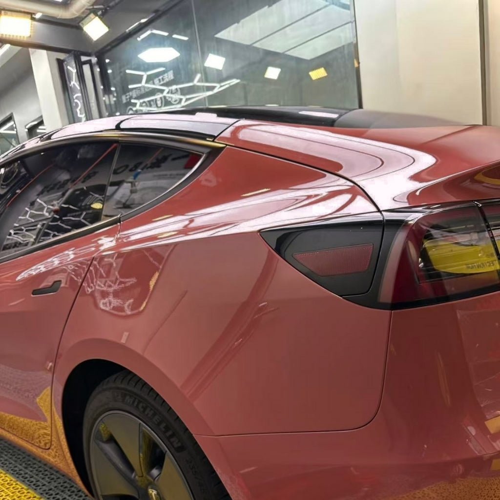 A red Tesla Model Y with Morganite Red Glossy SelfRepair Nano-Coated PPF is parked indoors under bright lights. Its glossy exterior, tinted rear windows, taillight, ochrana karosérie, and a yellow floor mat are all visible.
