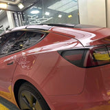 A red Tesla Model Y with Morganite Red Glossy SelfRepair Nano-Coated PPF is parked indoors under bright lights. Its glossy exterior, tinted rear windows, taillight, ochrana karosérie, and a yellow floor mat are all visible.