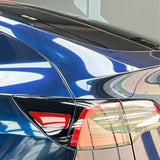 Close-up of a shiny blue car’s rear with Mystic Blue Glossy SelfRepair Nano-Coated PPF, highlighting the taillight, rear window, and trunk as indoor lighting reflects off its smooth, protected surface.