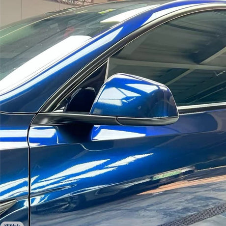 A close-up side view of a shiny blue car with Mystic Blue Glossy SelfRepair Nano-Coated PPF, focusing on the driver’s door, side mirror, and window, highlighting ochrana laku vozidla and vivid reflections on the car’s surface.