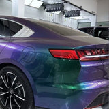 A close-up of a sleek car's rear with Red Blue Green Chameleon SelfRepair Nano-Coated PPF, fading from green to purple. Parked indoors under bright lights, the car’s shiny surface, modern tail lights, and advanced ochranná fólia na auto stand out.