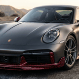 A matte gray Porsche with Red Forged Carbon Graphite Self-Healing Nano-Coated PPF accents and a carbon fiber finish is parked on pavement outdoors, mountains visible behind it at sunset.