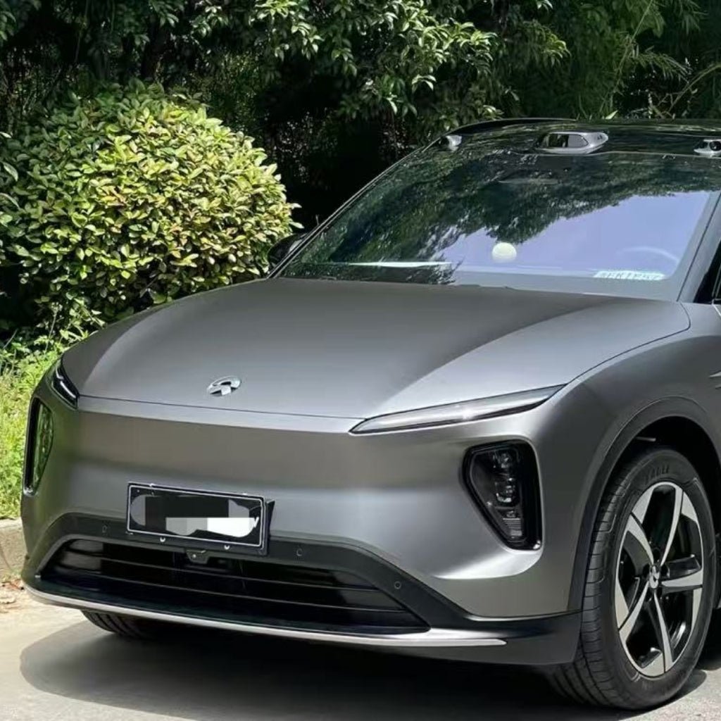A sleek, silver-gray electric SUV with a modern design is parked outdoors, featuring a smooth grille, slim headlights, and enhanced ochrana karosérie provided by the Silver Liquid Metallic Matte SelfRepair Nano-Coated PPF.