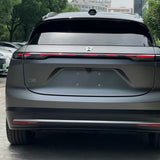 Rear view of a grey NIO ES6 electric SUV with sleek design and horizontal taillight bar, featuring Silver Liquid Metallic Matte SelfRepair Nano-Coated PPF for body protection. Trees and parked cars are visible in the background.