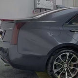A close-up side view of a sedan's rear section features the Sparkle Black Matte SelfRepair Nano-Coated Nexthor™ film, highlighting the taillight, fuel door, rear wheel, and trunk while parked indoors.